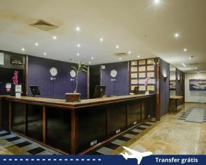 a hotel lobby with a reception desk and clocks on the wall at Rio Aeroporto Hotel Galeão in Rio de Janeiro