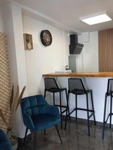 a kitchen with a bar with three chairs and a clock at Corail Azur Terre Sainte in Saint-Pierre +42 photos