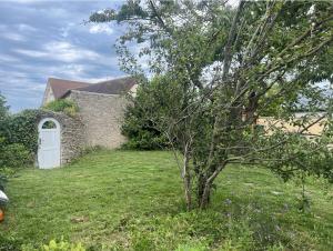 un albero davanti a una casa con una porta di Gîte à 3 minutes à pied de la mer a Bernières-sur-Mer