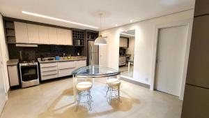 a kitchen with a glass table and stools in it at Loft Amplo e Aconchegante c/ Quarto Privativo in Campo Grande