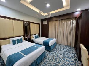 Habitación de hotel con 2 camas en azul y blanco en هدوء الليالي للأجنحة الفندقية en Khamis Mushayt