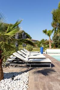 - une rangée de chaises longues blanches à côté de la piscine dans l'établissement LES LODGES TAIZEN, séjour SPA- sans enfants, à Saint-Cannat