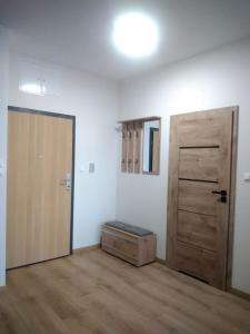 an empty room with a door and a room with wood floors at Uniejów Apartament in Uniejow