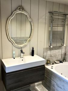 een badkamer met een wastafel, een spiegel en een bad bij Ducks Wharf in Hampton