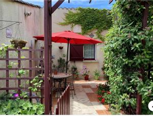 a patio with a table with a red umbrella at La Vignalié in Orban