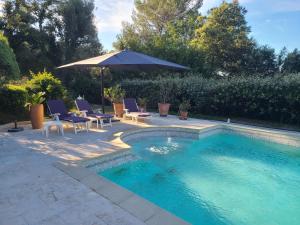 einen Pool mit Stühlen und einem Sonnenschirm in der Unterkunft Villa Mycènes in Garéoult