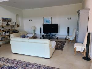 ein Wohnzimmer mit einem weißen Sofa und einem TV in der Unterkunft Villa Mycènes in Garéoult