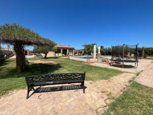 a park bench sitting in the grass next to a tree at La Estacada in Lora del Río