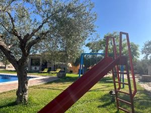 a red slide next to a tree next to a pool at La Estacada in Lora del Río