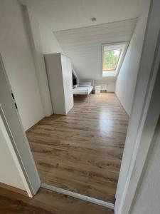 een zolderkamer met een houten vloer en een raam bij Kopp in Lohfelden