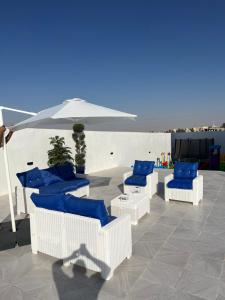 Amman villa في عمّان: مجموعة من الكراسي الزرقاء ومظلة على الفناء