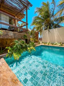 a swimming pool in front of a house with palm trees at Vila do Alto - Beach Homes in Itarema