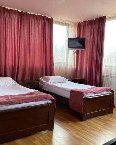 Duas camas num quarto com cortinas vermelhas e uma televisão em RL Hotel em Stepanavan