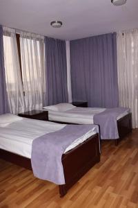 2 camas num quarto com paredes roxas e pisos em madeira em RL Hotel em Stepanavan