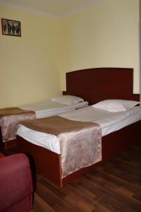 2 camas individuais num quarto com uma cadeira vermelha em RL Hotel em Stepanavan