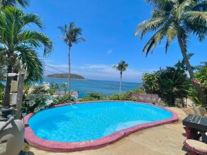a swimming pool with the ocean in the background at Naiharn On The Rock Resort Phuket in Nai Harn Beach