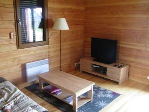 uma sala de estar com uma mesa e uma televisão em Chalet du frêne à Laguiole em Laguiole