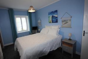 niebieska sypialnia z białym łóżkiem i oknem w obiekcie La Charentaise des Lilas w mieście Saint-Léger