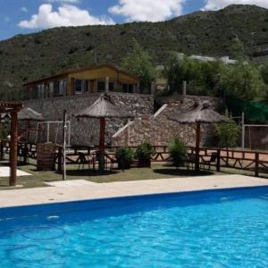 - une piscine avec des tables et des parasols en face d'une maison dans l'établissement Cabañas Gemas del Lago, à Potrero de los Funes