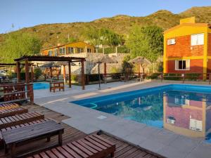 a swimming pool with tables and chairs and a building at Cabañas Gemas del Lago in Potrero de los Funes