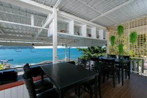 a dining room with tables and chairs and a view of the ocean at Naiharn On The Rock Resort Phuket in Nai Harn Beach