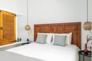 a bedroom with a white bed with a wooden headboard at Fragma suite in Faneroméni