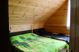 a room with a bed in a wooden cabin at Hillside Bakhmaro in Chʼkhakoura