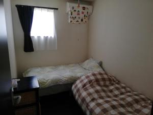 niewielka sypialnia z łóżkiem i oknem w obiekcie YUFUKANⅡ w mieście Yufu