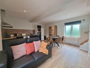 sala de estar con sofá de cuero negro y mesa en Maison T3 Mérignies, en Mérignies