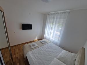 a white bedroom with a bed and a television at Nina Apartman 3 in Soko Banja