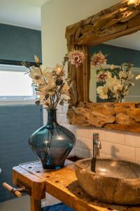 a vase with flowers on a table next to a sink at Vakantiewoning Le Garaazje in 's-Gravendeel