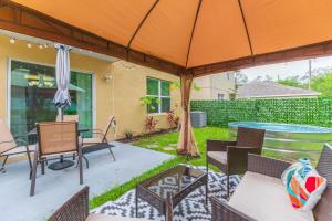 un patio con mesa, sillas y sombrilla en Modern Luxury Tampa Home - Splash Pool - Game Room en Tampa