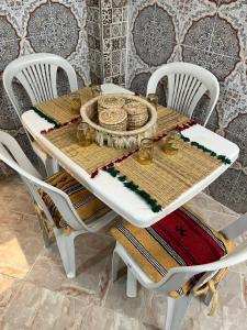 einem weißen Tisch mit Stühlen und einer Tischdecke darauf in der Unterkunft Une maison au centre de l'ancienne Médina in Marrakesch