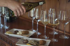 a person pouring wine into a plate of food and wine glasses at Alte Villa G&auml;stehaus in L&uuml;deritz