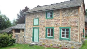 una antigua casa de ladrillo con ventanas con persianas verdes en Le Fournil de Hourt, en Vielsalm