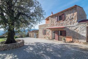 an external view of a stone house with a tree at La Dimora degli Dei in Piras