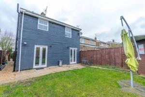 a blue house in a yard with a fence at 5 Bedroom 5 Bath sleeps 10 close Luton Airport M1 in Caddington