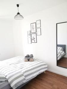 a white bedroom with a bed and a mirror at LE GOURMAND *T2 (40m²) *WIFI*PARKING PRIVE*CALME in Lourdes