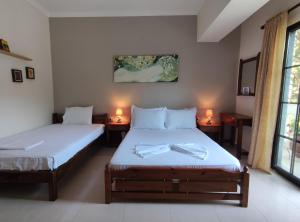 two beds in a room with two lamps on tables at Evripidis – Katerina Rooms –Β in Asprovalta