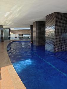 uma grande piscina com água azul num edifício em Clarke's Landscape Apartment 303 Gold B Nascente Sombra em Fortaleza