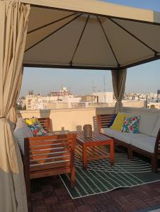 a patio with two benches and a couch and an umbrella at Rainbow 7th floor penthouse apartment in Engomi