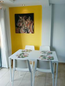 a white table and chairs in a room with a painting of zebras at Rainbow 7th floor penthouse apartment in Engomi