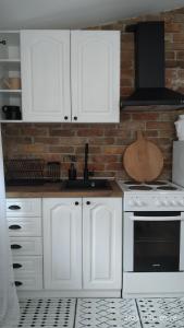 a kitchen with white cabinets and a brick wall at Apartman Stara Trešnja in Kladovo