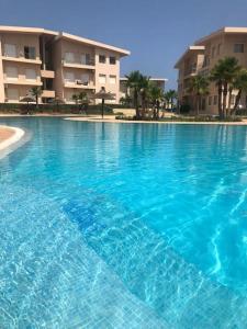 a large blue swimming pool in front of a building at Résidence avec piscine Kenz Mehdia in Kenitra