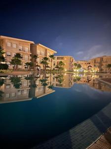 a large swimming pool with palm trees and buildings at Résidence avec piscine Kenz Mehdia in Kenitra