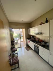 a kitchen with white cabinets and a stove top oven at Résidence avec piscine Kenz Mehdia in Kenitra