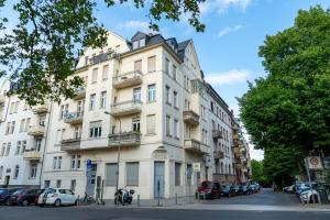a large white building with cars parked on the street at Altbau-Apartment im Westend I Küche I Hochparterre in Wiesbaden
