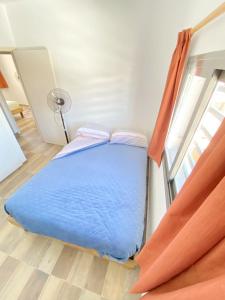 Un dormitorio con una cama azul y una ventana. en Depto cerca de Palmares Shopping Mall, en Godoy Cruz