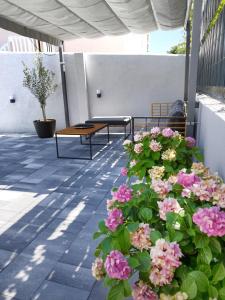 eine Terrasse mit zwei Bänken und rosa Blumen in der Unterkunft Holiday home Maslina in Orebić