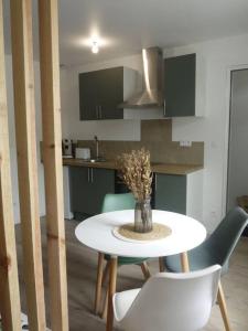 einen Tisch mit Stühlen und eine Vase darauf in der Küche in der Unterkunft Appartement avec terrasse in Mussidan